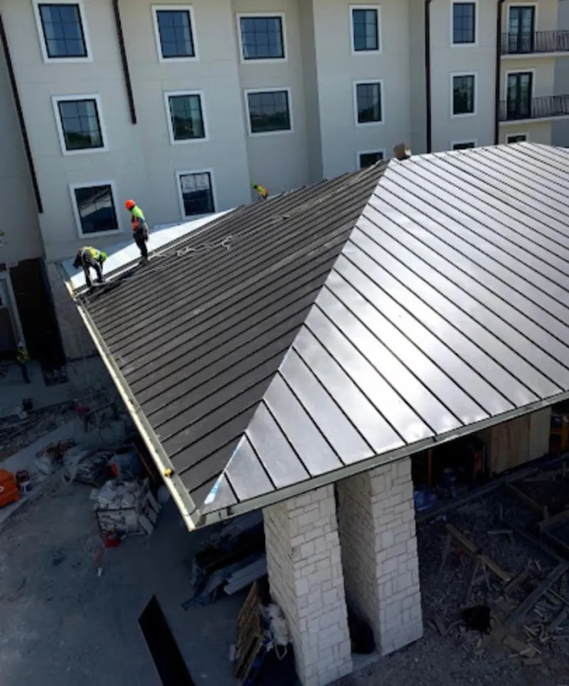 Crew installing standing seam metal roof panels on a commercial project in Pace